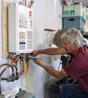 Plumber Working on Tankless Water Heater Plumber Working on Tankless Water Heater