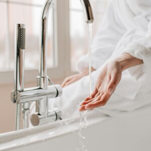Woman's hand tests water from a bathtub faucet