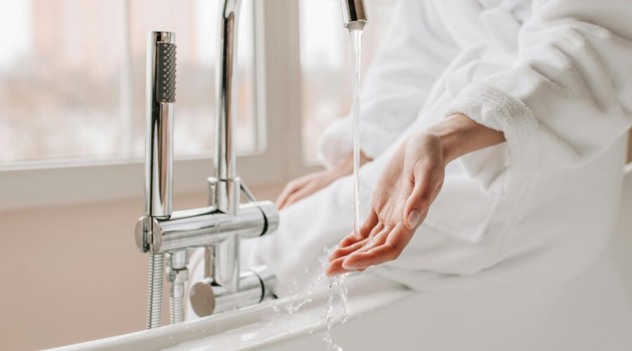 Woman's hand tests water from a bathtub faucet